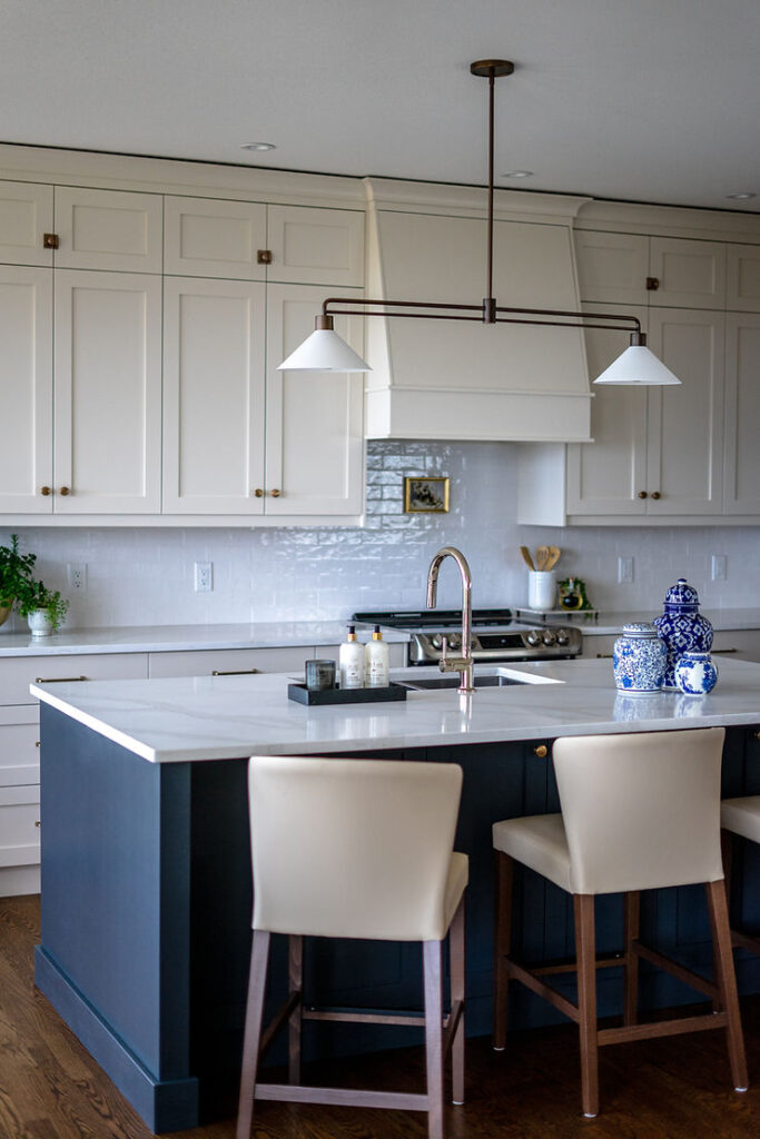 Transitional cream kitchen with navy island, modern island light