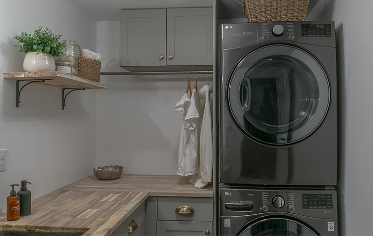 Sage green laundry room with butcher block cabinetry stacker washer dryer