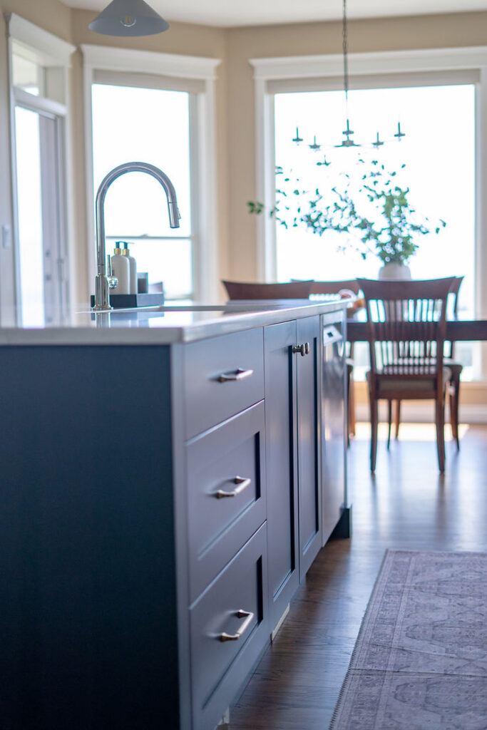 Transitional cream kitchen with navy island, modern island light