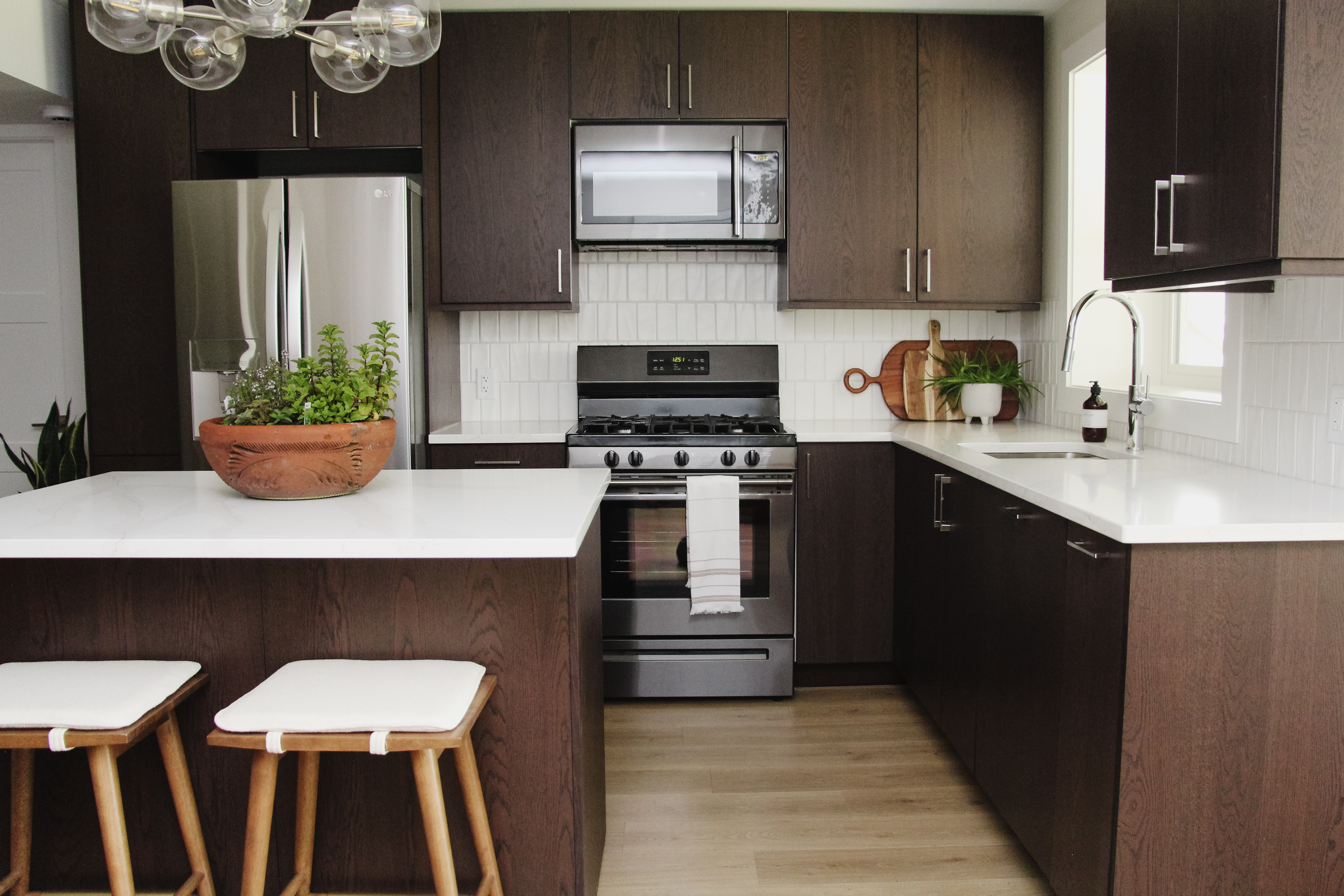 MCM basement suite kitchen, walnut veneer cabinets, quartz, vertical subway tile backsplash