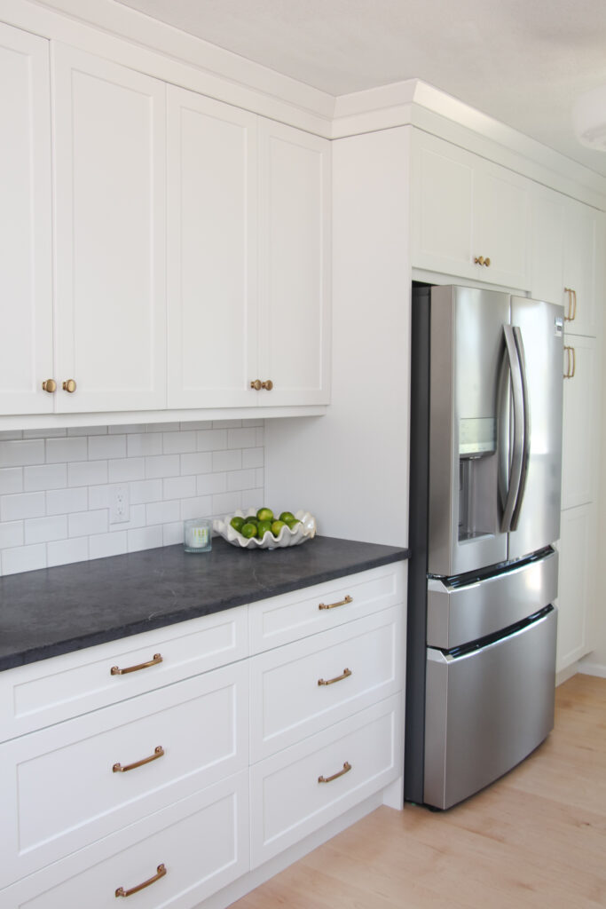 white galley kitchen with black quartz countertop, bowl of limes, gold hardware