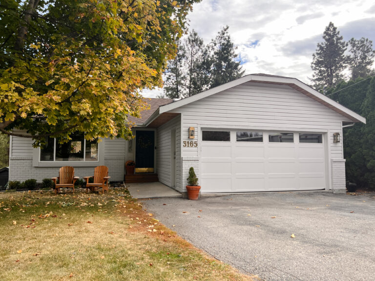 White rancher house with gold lanterns and navy blue door