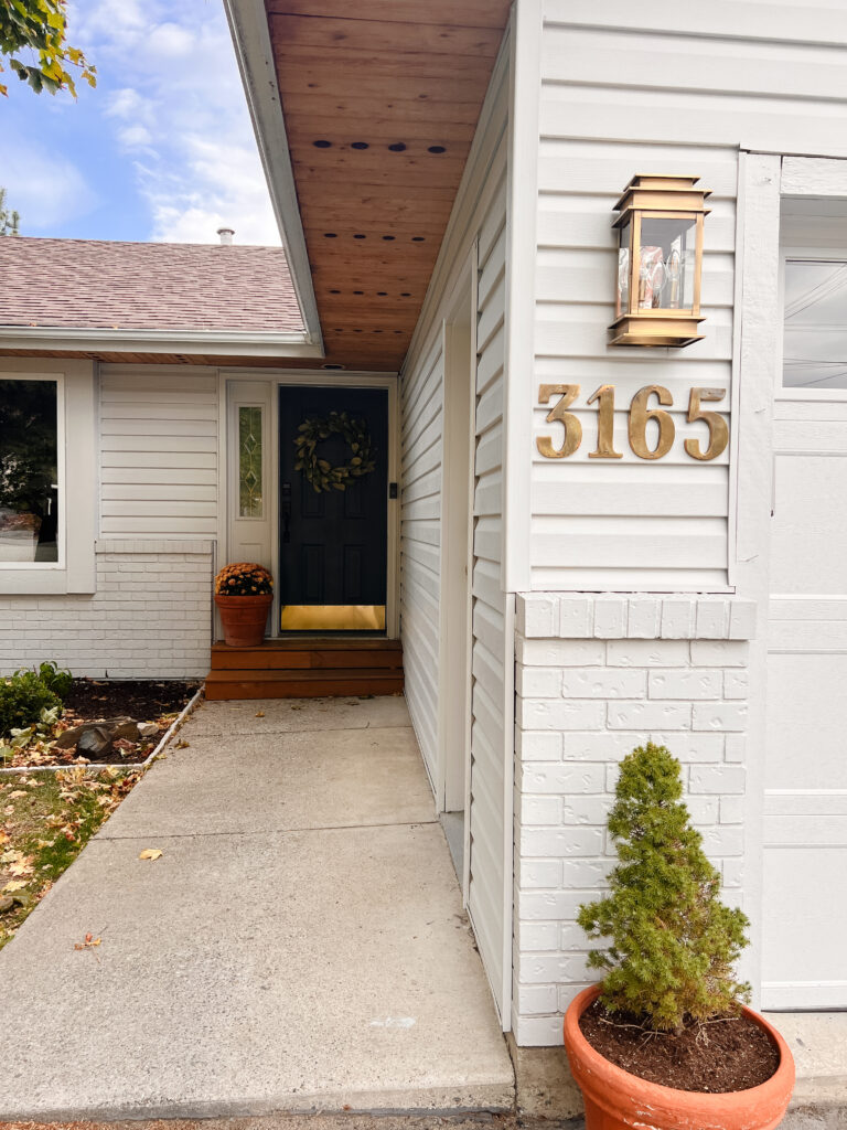 White rancher house with gold lanterns and navy blue door