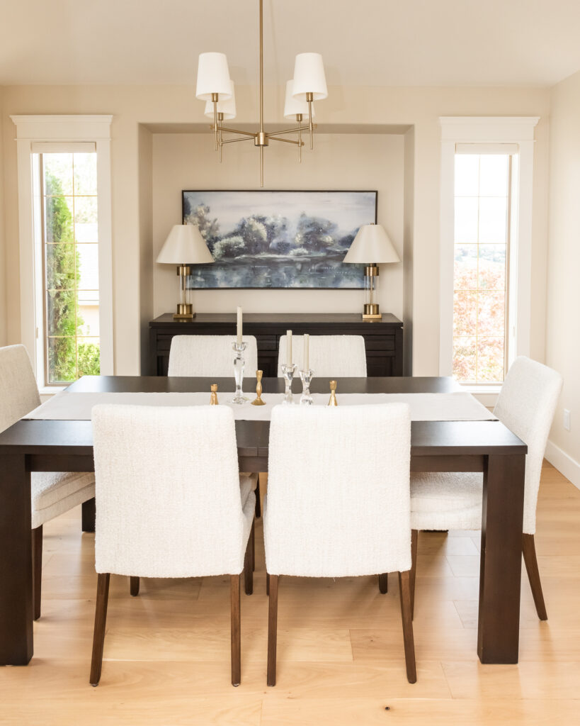 Dining room with cream boucle chairs and dark table, gold lighting