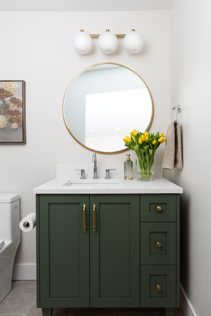 basement bathroom with green vanity and round mirror and tulips
