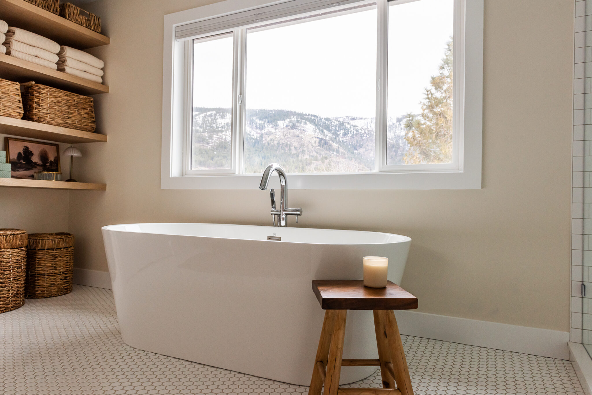 transitional primary ensuite, warm wood tones and white tile, stand alone tub under window