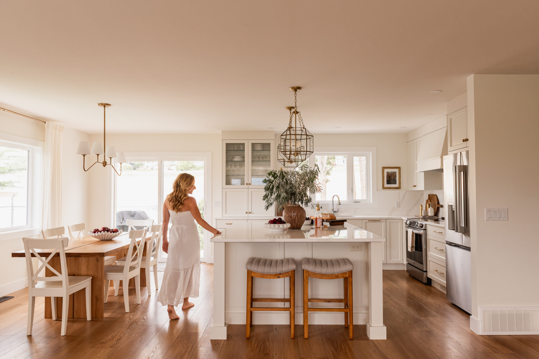 woman walking through open concept white kitchen