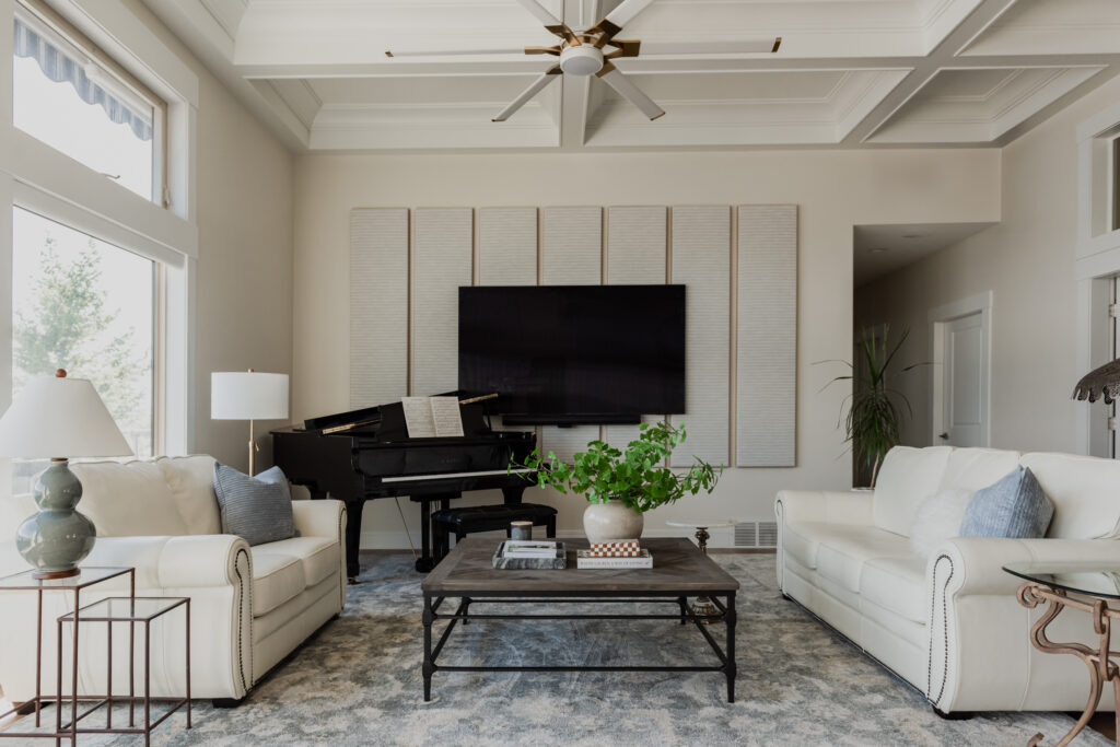Living room with grand piano, upholstered seating, coffee table, and custom acoustic wall panels for sound control.
