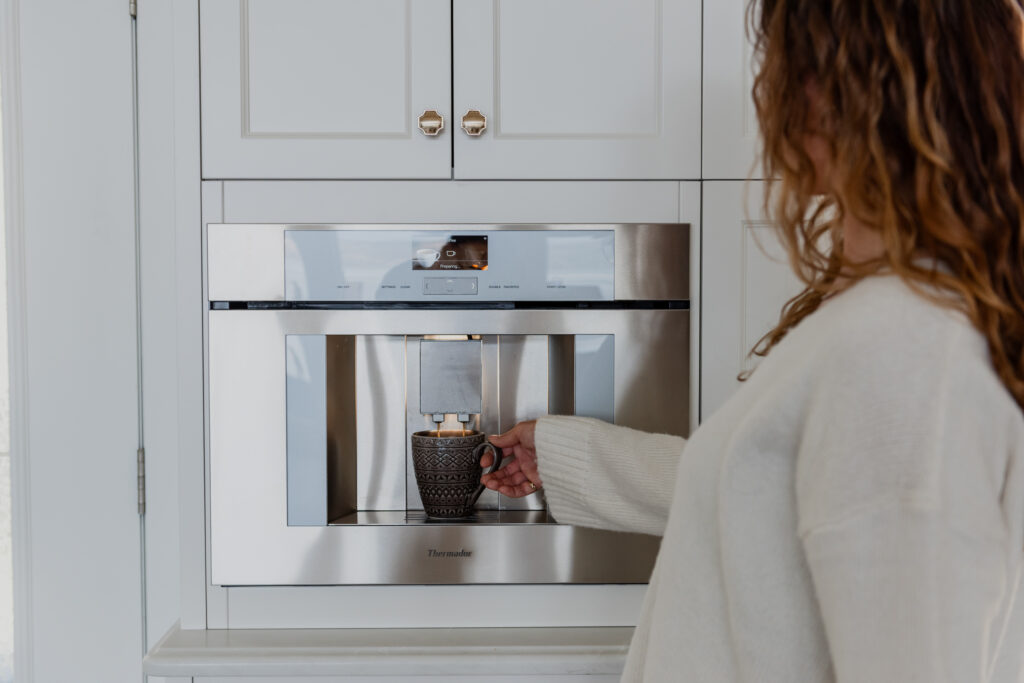 Woman in Kitchen making coffee with integrated Thermador built in coffee maker
