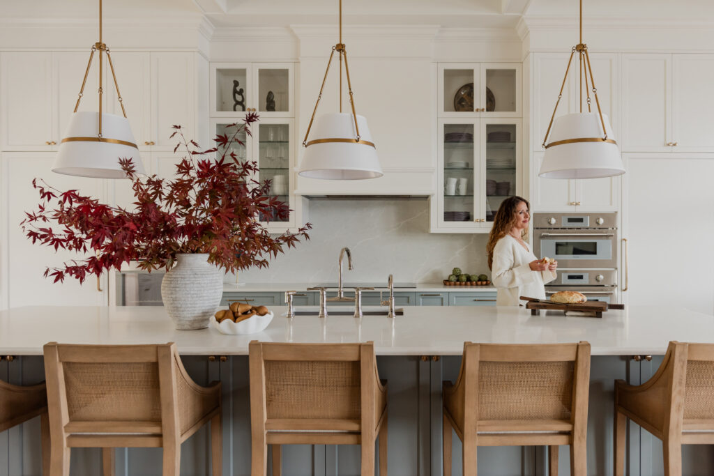 Woman in Custom 6-foot range hood feature wall with integrated Thermador appliances, coffered ceilings, and a spacious entertaining island.