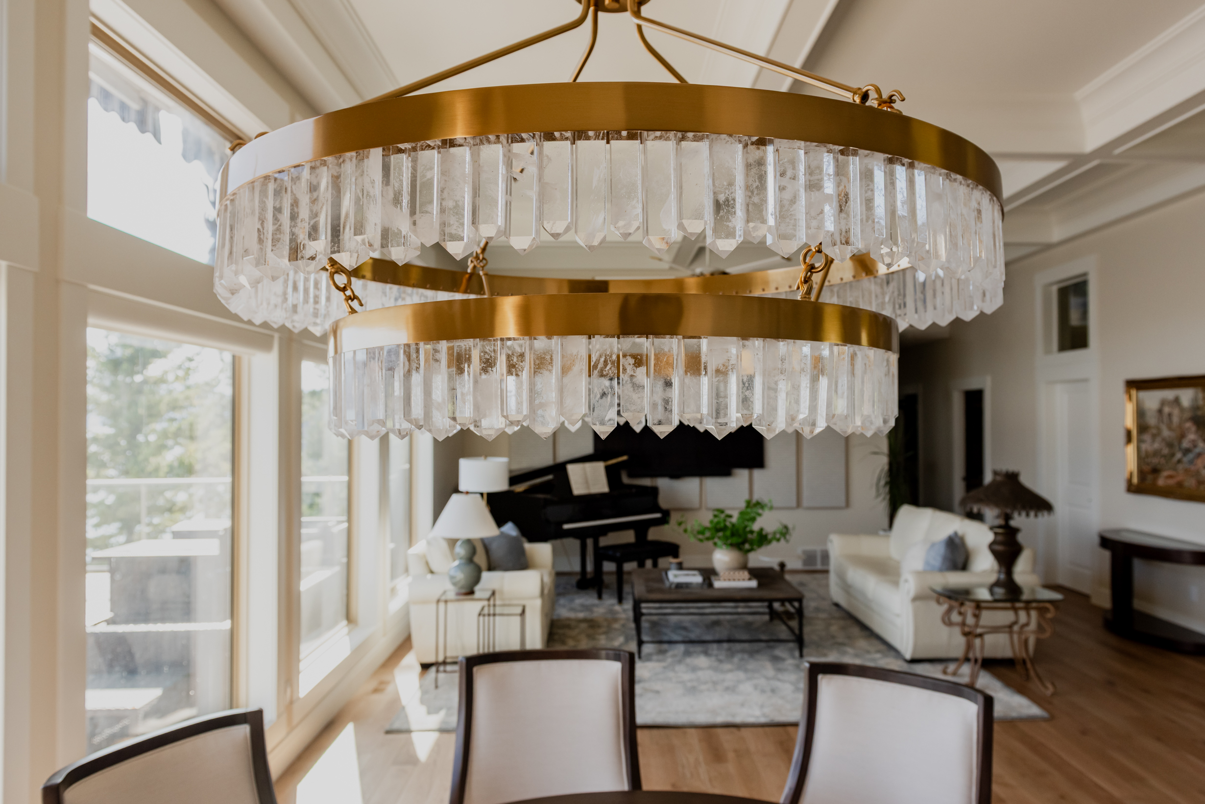 Warm brass chandelier with natural calcite crystal tiers, suspended in a dining space with 12-foot ceilings.