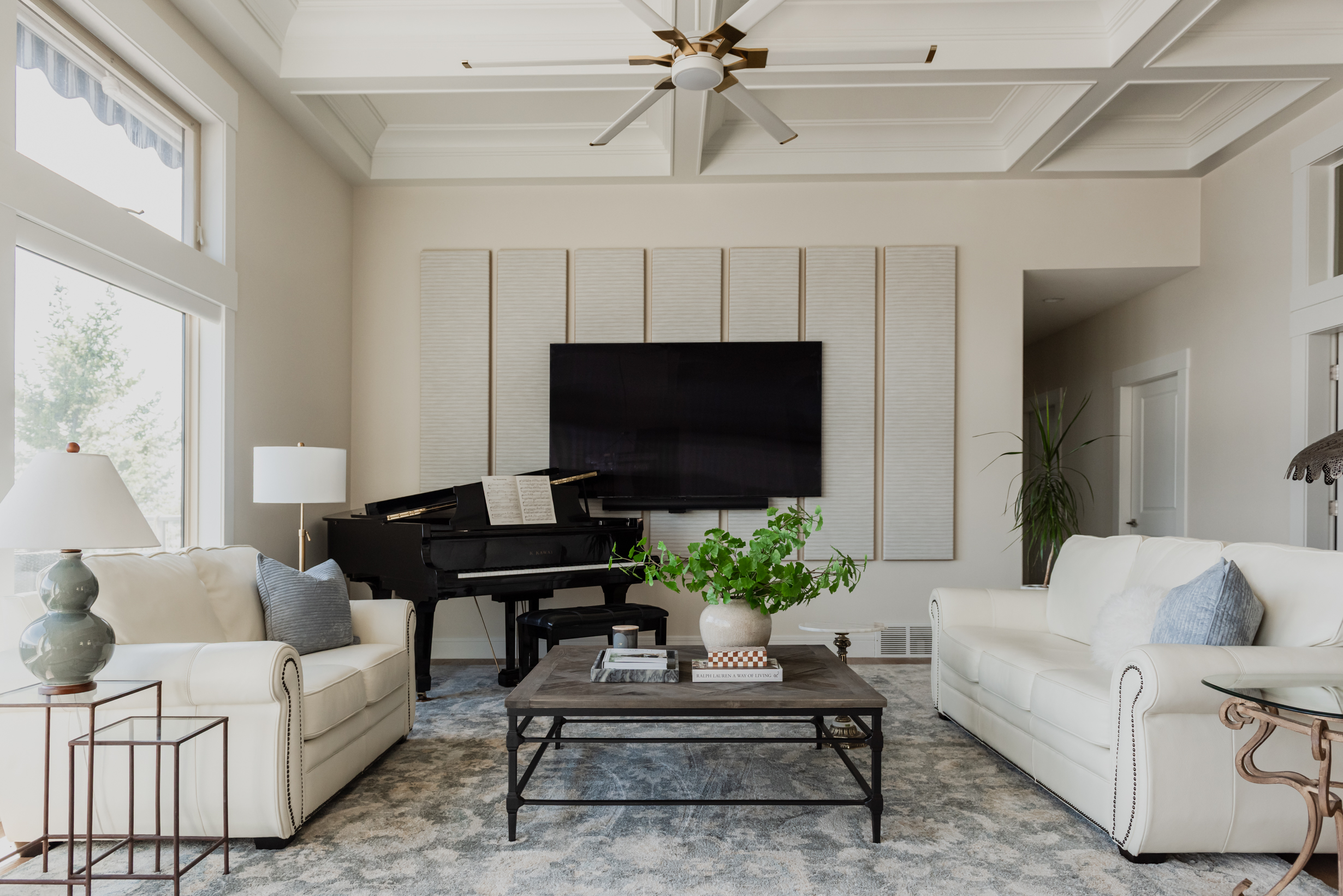 Living room with grand piano, upholstered seating, coffee table, and custom acoustic wall panels for sound control.