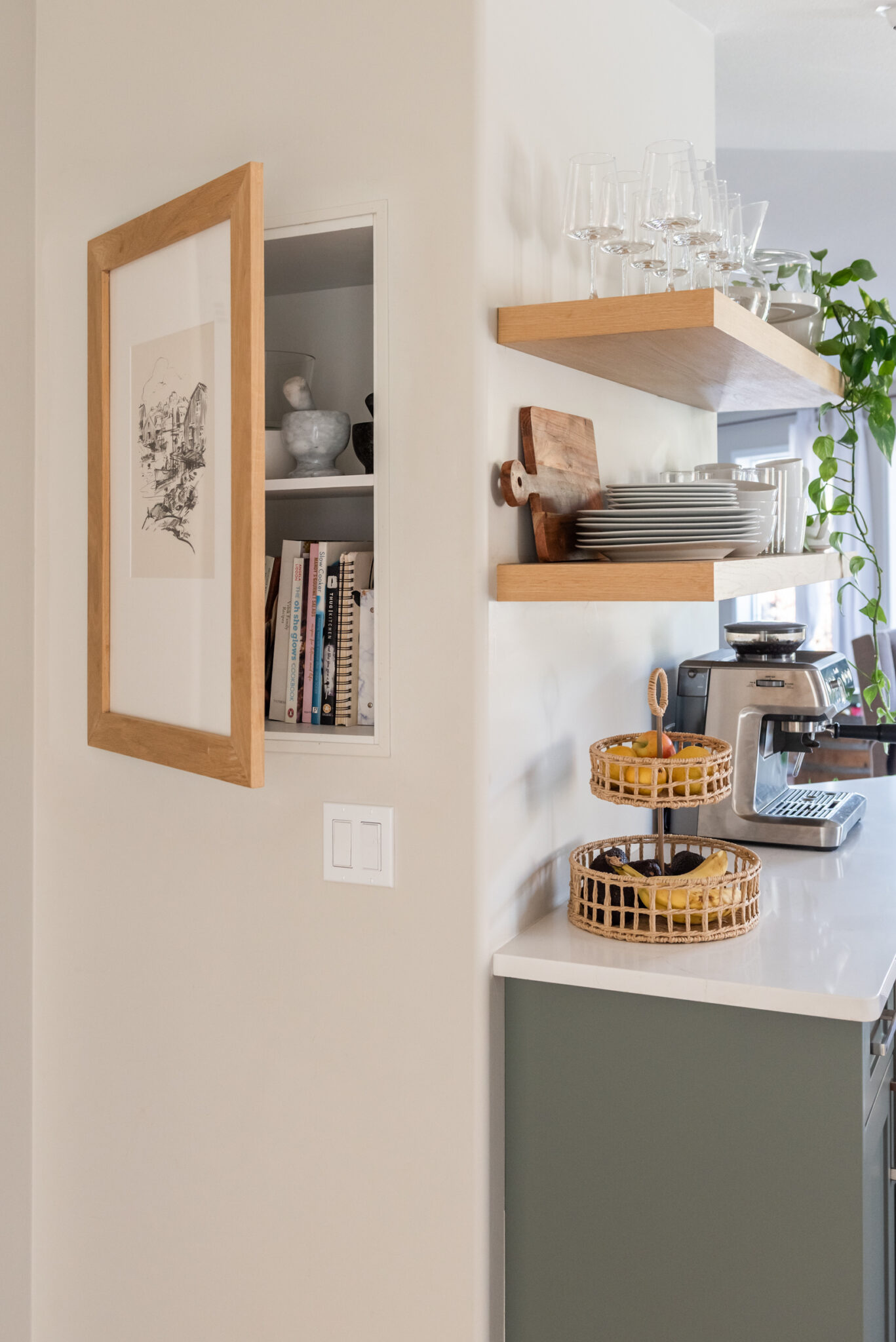 Kitchen wall detail showing flush framed art panel that opens to reveal concealed storage behind.