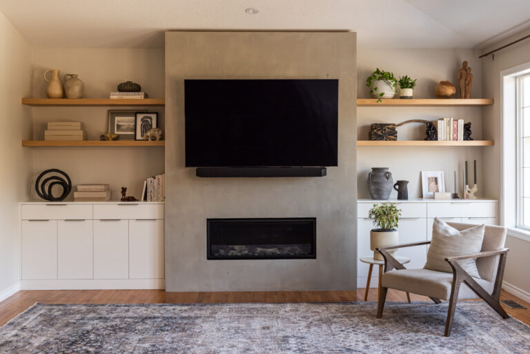 Modern living room with zero clearance fireplace, hand plastered surround, white oak floating shelves, and custom built in cabinetry for concealed storage.