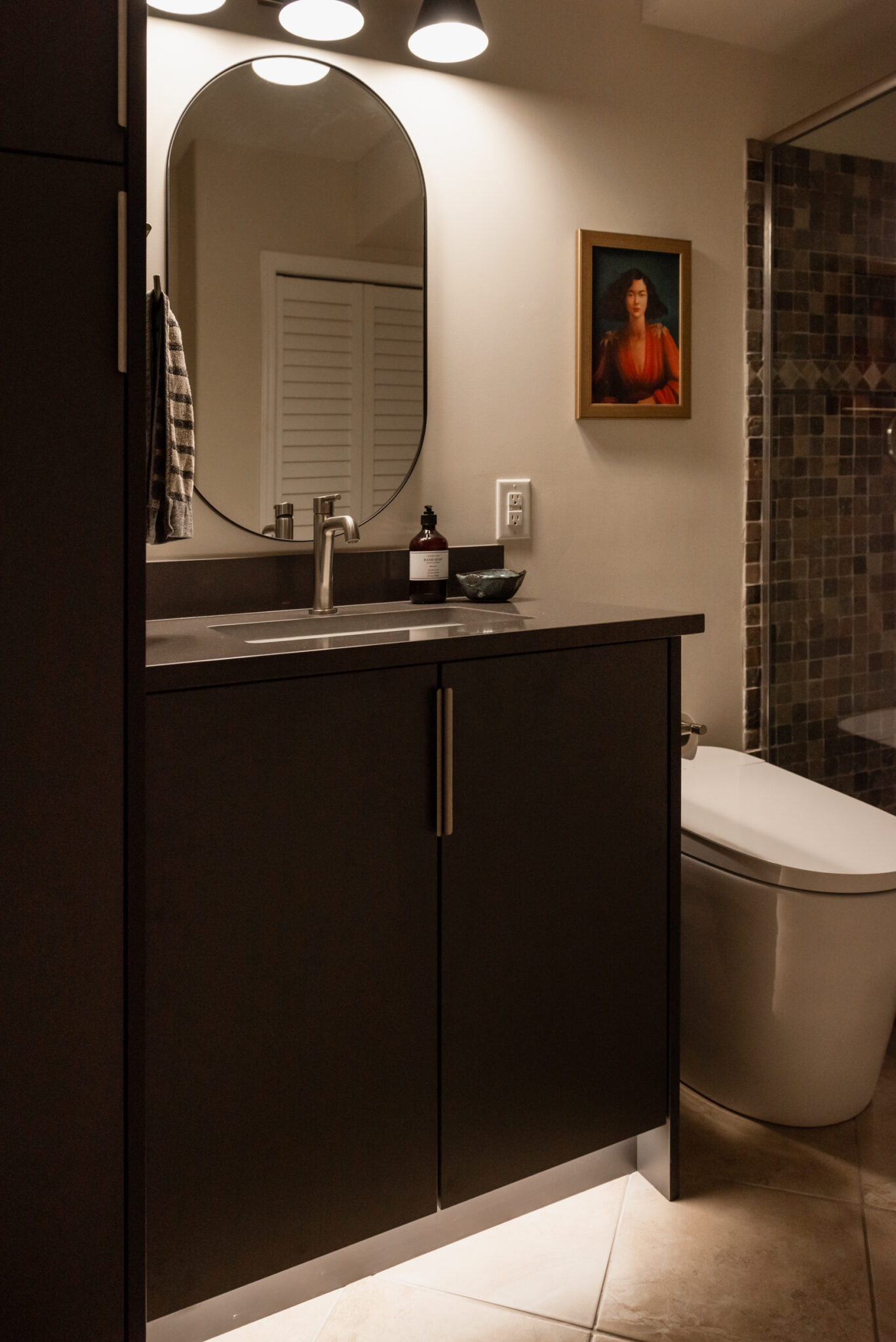 Basement bathroom vanity with dark cabinetry, integrated toe kick lighting, and modern faucet for a budget friendly refresh.