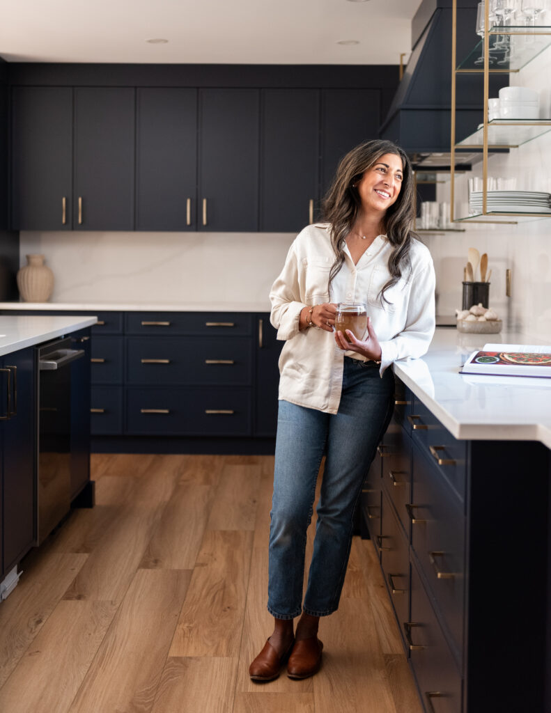Women in bright renovated kitchen with large island, navy blue cabinetry, and warm wood accents in a family-focused home renovation