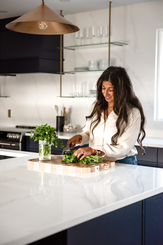 Women in bright renovated kitchen with large island, navy blue cabinetry, and warm wood accents in a family-focused home renovation