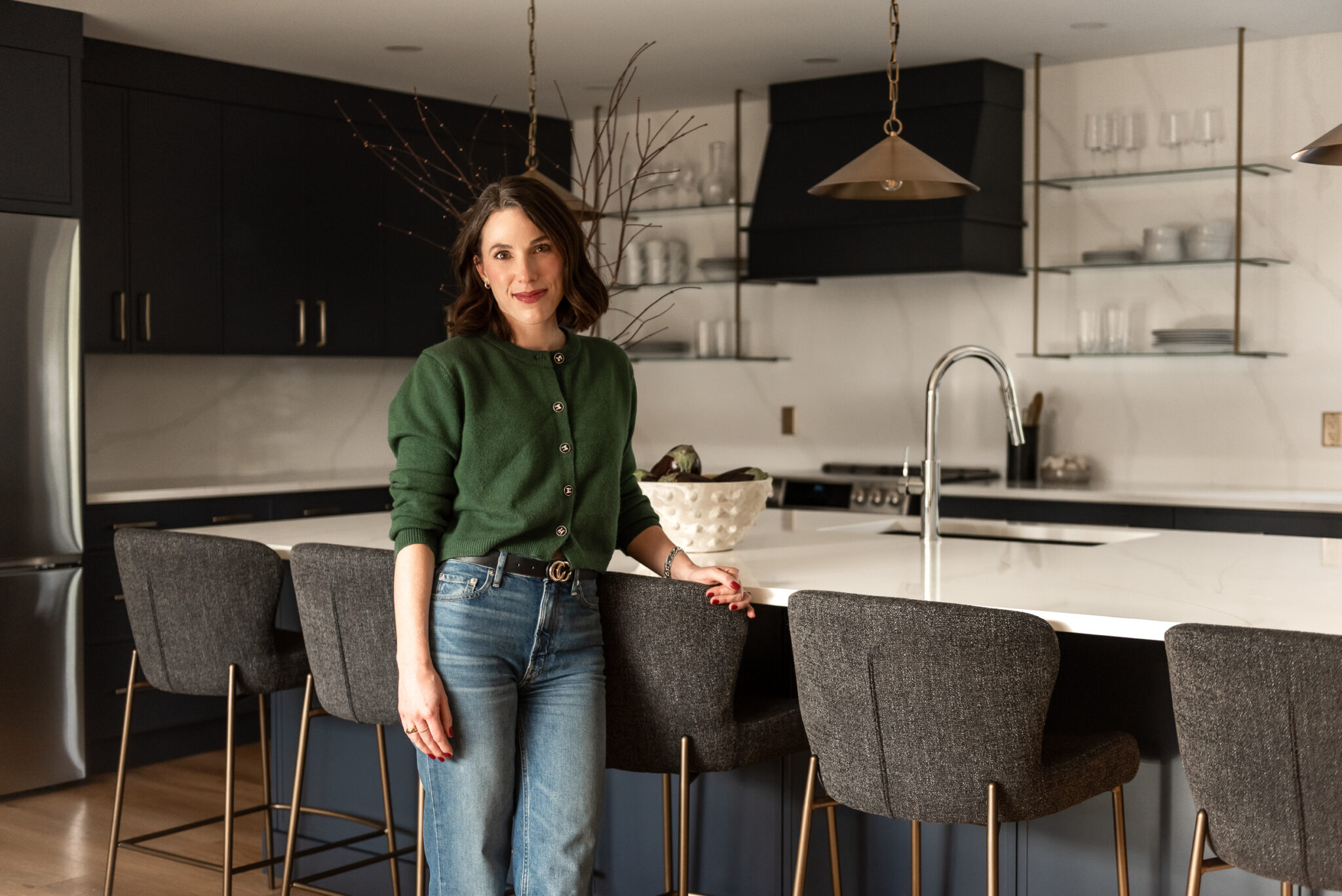 Woman in bright renovated kitchen with large island, navy blue cabinetry, and warm wood accents in a family-focused home renovation