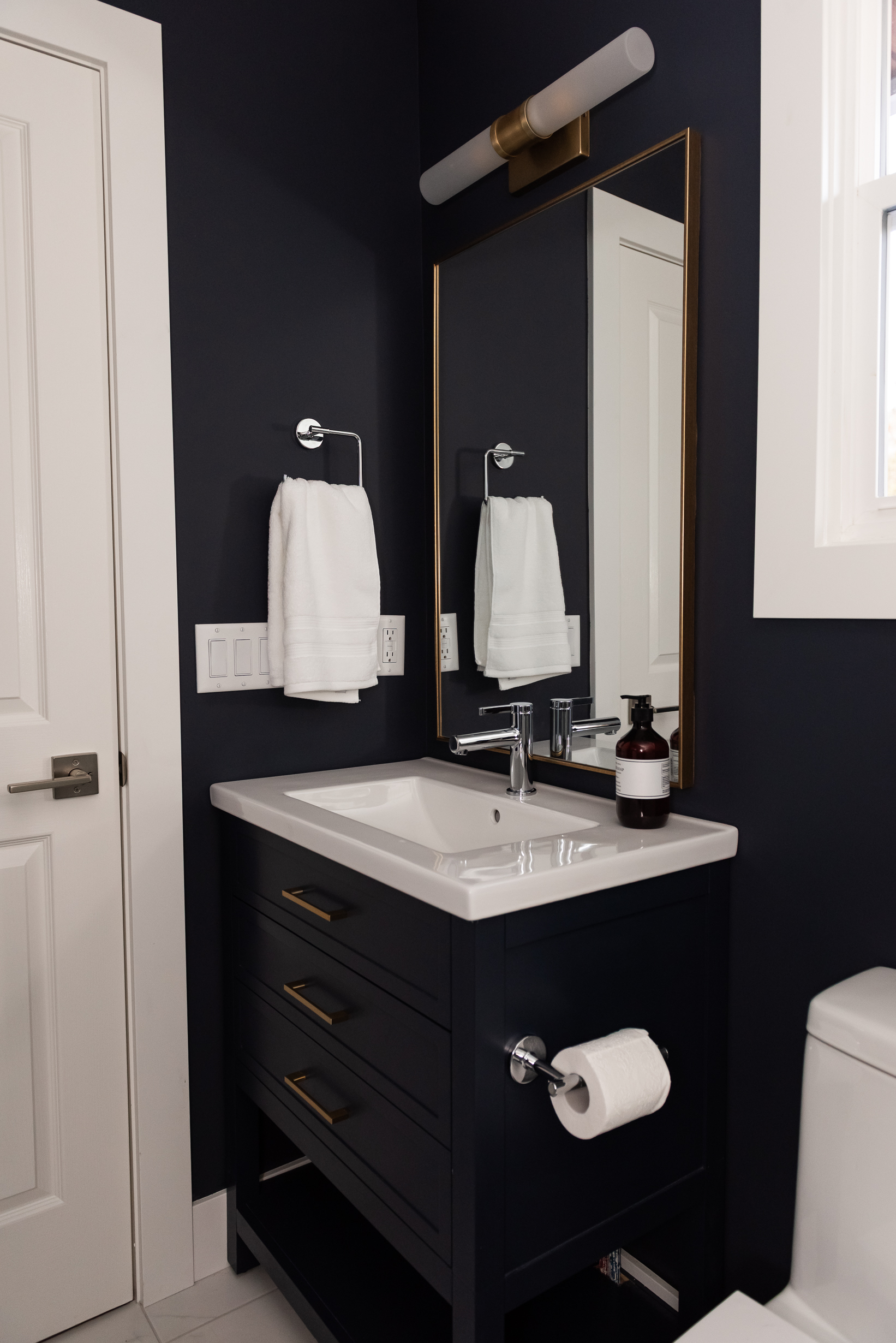 Small ensuite with colour drenched navy vanity and marble look tiled shower