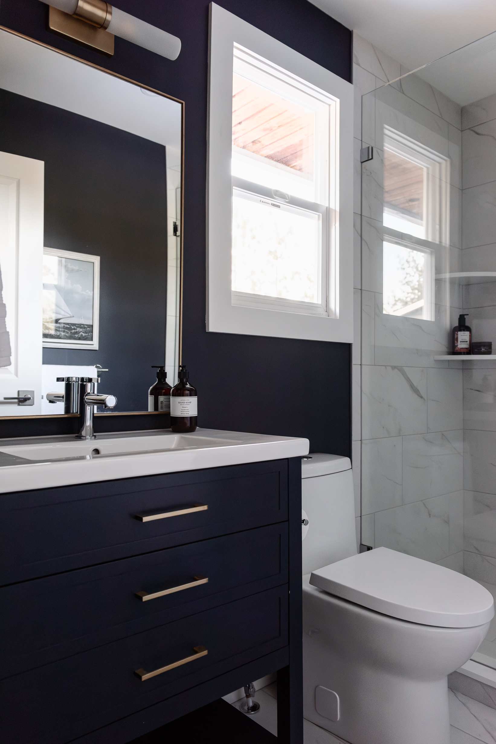 Small ensuite with colour drenched navy vanity and marble look tiled shower