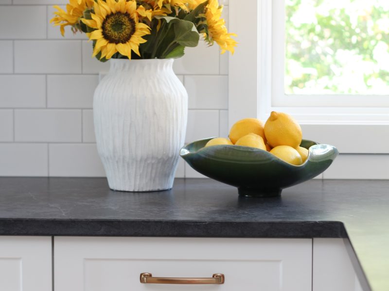 timeless white kitchen cabinets, black quartz counter, gold hardware, sunflowers and lemon decor, subway tile to ceiling